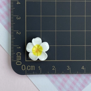Detailed view of a 2cm white resin plumeria flower accessory measured against a ruler
