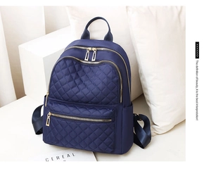 Close-up of quilted navy blue waterproof backpack featuring elegant golden hardware zippers