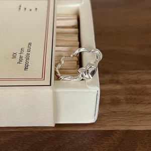 Detailed shot of S925 sterling silver twisted rope ring with heart charm on wood