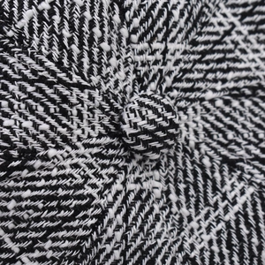 Close-up of black and white herringbone tweed fabric and covered button on newsboy cap