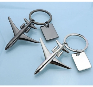 Detail of metal airplane keychains in black and silver finishes on a reflective blue surface