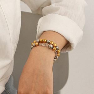 Bracelet à perles bicolores en or et argent sur le poignet d'un mannequin femme