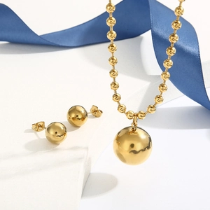 Detailed view of gold bead necklace and stud earrings set with elegant blue ribbon decoration