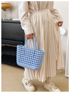 Detail of blue hollow woven jelly bag held by a model in a summer resort outfit
