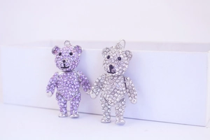 Detailed view of cute purple and white crystal rhinestone bear pendants on a clean base