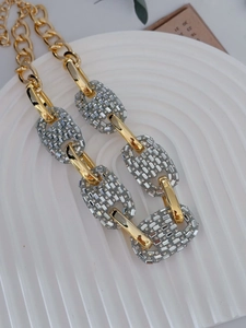 Macro view showing detailed pavé rhinestones on vintage gold-toned pig nose chain links
