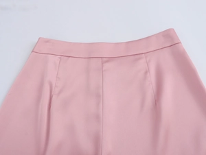 Gros plan d'un pantalon en satin rose montrant la coupe et le tissu brillant