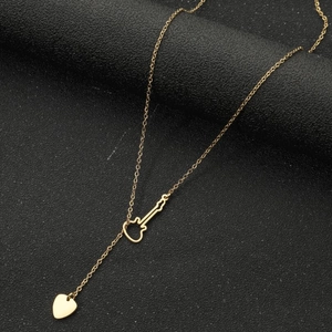 Collier en acier titane doré avec pendentif violon et breloque cœur sur fond noir texturé