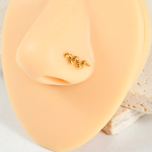 Vue détaillée d'un piercing de nez en forme de serpent doré sur un modèle en silicone