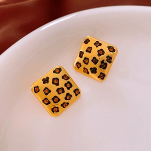 Gros plan de boucles d'oreilles vintage léopard carrées avec base dorée et strass orange
