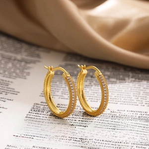 18K gold hoop earrings with micro-set zircon stones on vintage newspaper background