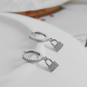Détail des boucles d'oreilles huggie en argent s925 avec pendentifs cadenas et pavé de zircons
