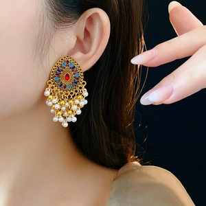 Gros plan de boucles d'oreilles Jhumka vintage avec émail coloré et glands en perles