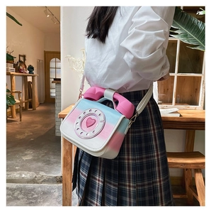 Close-up view of a creative gradient pink and blue telephone-shaped crossbody bag worn by a model