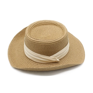 Detailed close-up of woven straw texture and soft beige fabric ribbon on a sun hat