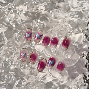 Pink gradient press-on nails set with 3D butterfly, pearls, and gold glitter accents