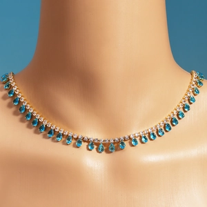 Detail of gold-plated necklace with blue teardrop zircon pendant on a model bust
