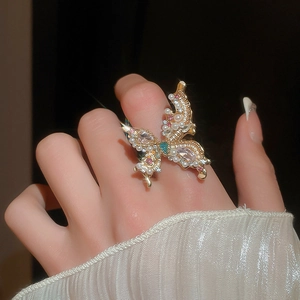 Close-up of golden butterfly ring with pearls, rhinestones, and green gemstone detail