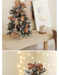 Detail of mini snow-flocked Christmas tree with pine cones, ribbons and LED fairy lights
