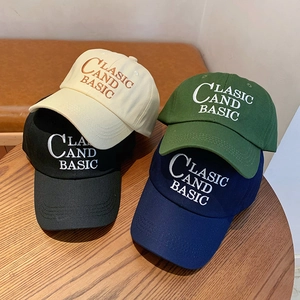 Detailed view of four cotton baseball caps in classic colors on a rustic wooden table