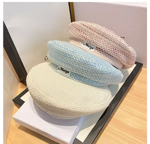 Detailed close-up of mixed-color knitted beret hats featuring the Mniya woven label