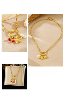 Macro shot of gold-plated necklace charms including red cherries, starfish, and shells