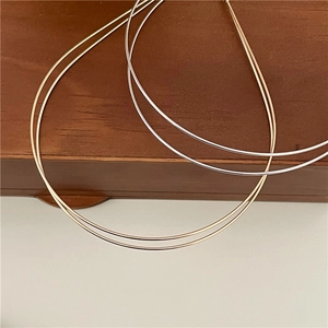 Detail shot of minimalist gold and silver slim metal collars on a wooden display box