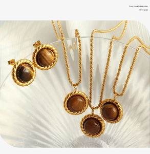 Detail of vintage tiger eye jewelry set with gold twist edges on a textured glass bowl