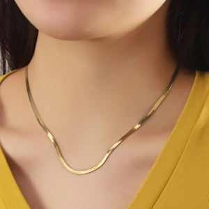 Collier maille serpent en acier inoxydable doré 18 carats porté par un mannequin femme