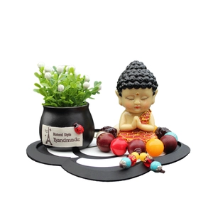 Zen Buddha figurine set with miniature plant and prayer beads on a black floral base