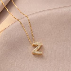Gold letter Z necklace with zircon pendant on silk background for elegant women's style