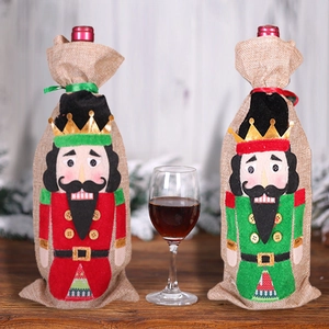 Nutcracker Christmas wine bottle covers in red and green burlap on a wooden table