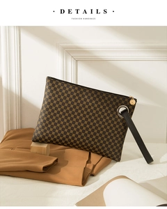 Detail view of brown crocodile texture envelope clutch bag with zipper and wrist strap
