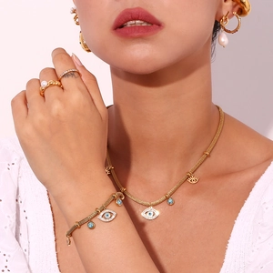 Close-up of 18K gold plated jewelry set featuring evil eye charms and turquoise accents
