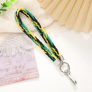 Macro shot of yellow, green, and black woven lanyard with silver metal lobster clasp