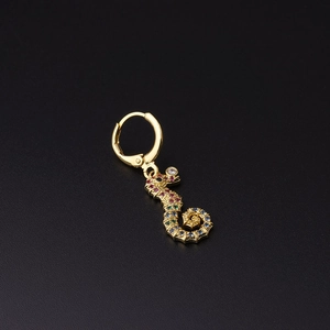 Golden seahorse earring with colorful zircon stones on a black textured background