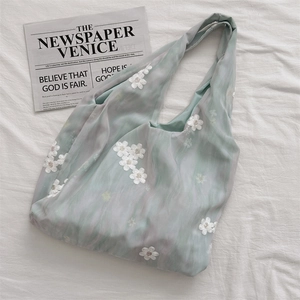 Close-up of tie-dye tote bag with delicate white floral embroidery and sheer fabric