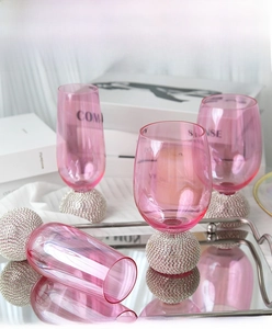 Verres à whisky roses avec pied orné de diamants posés sur un plateau miroir