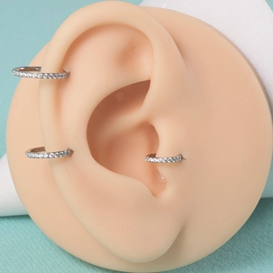 G23 titanium nose rings with cubic zirconia inlay on a teal background