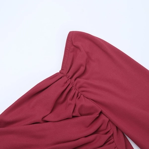 Gros plan détaillé des coutures et plis sur une robe bordeaux à épaules dénudées