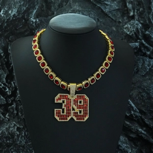 Détail du collier doré avec pendentif numéro 39 serti de cristaux rouges