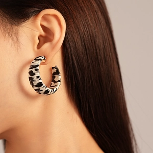 Gros plan de boucles d'oreilles en C avec motif zèbre noir et blanc et finition dorée