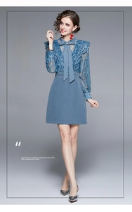 Détail d'une robe en dentelle bleu-gris avec col à nœud et manches à volants