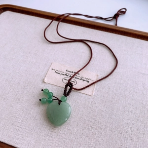 Detailed macro view of heart-shaped green aventurine stone pendant with braided rope