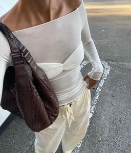 Photo street style d'un haut en maille blanche avec un grand sac en cuir tressé chic