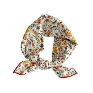 White floral print square scarf with orange borders tied in an elegant ring loop style