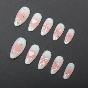 Almond-shaped almond press-on nails with pink heart, bow, and rhinestone details
