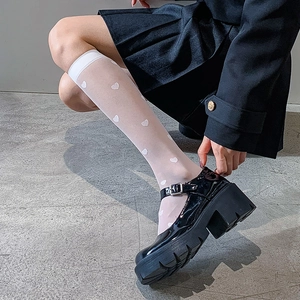 Detail of white heart pattern sheer knee-high socks paired with black Mary Jane shoes
