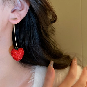Gros plan d'une boucle d'oreille fraise étincelante avec strass rouges et pendentif or