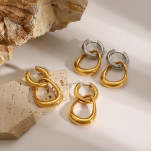 Minimalist gold and silver stainless steel hoop earrings on natural stone platform